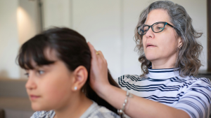 Parent examining a lice egg on finger during a head check