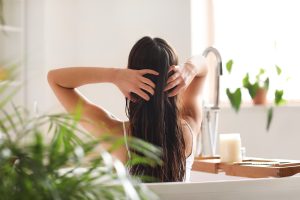 Parent applying coconut oil to a child's hair as a home lice remedy in a bright bathroom.