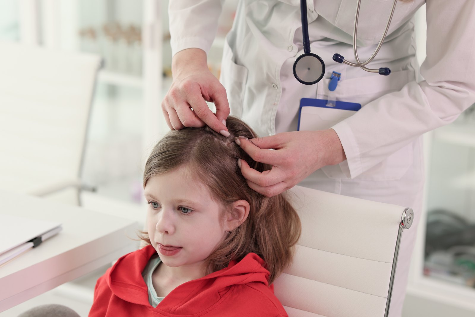 An Omaha parent looks closely at a small speck on a fingertip after checking a child's hair, deciding whether it is a live head louse, a nit, or ordinary scalp debris.
