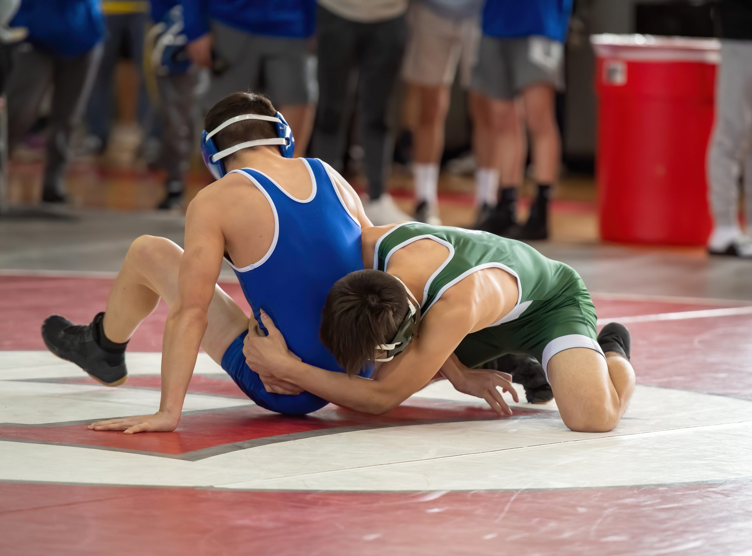 Youth wrestlers competing on a mat during a school sports match.