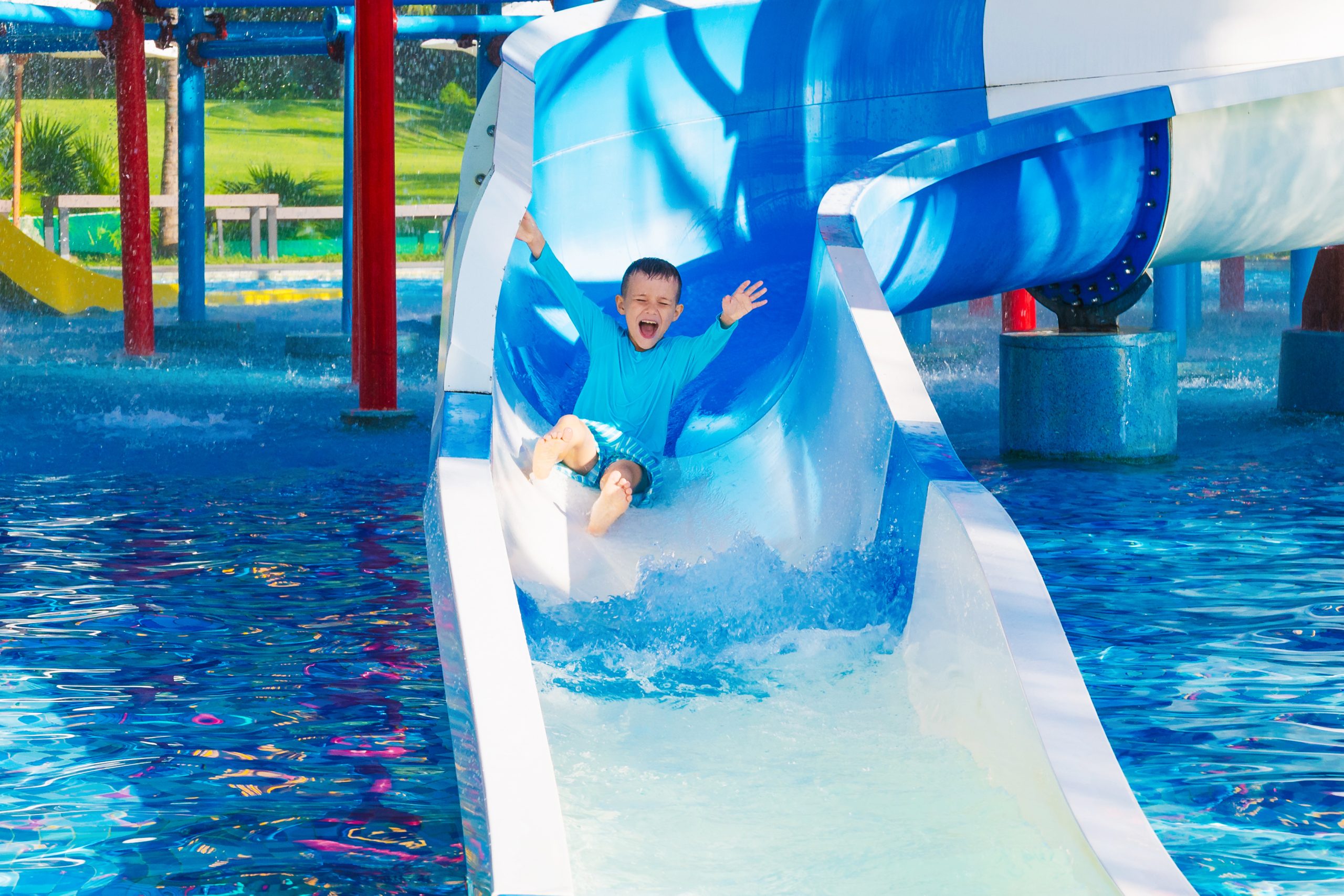 Child sliding into a water park pool during summer vacation.