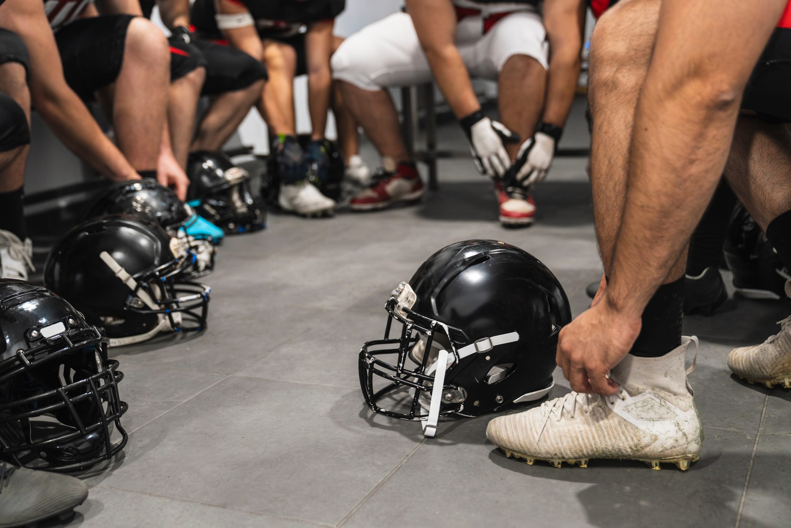 Student athletes getting ready with football helmets in a locker room.